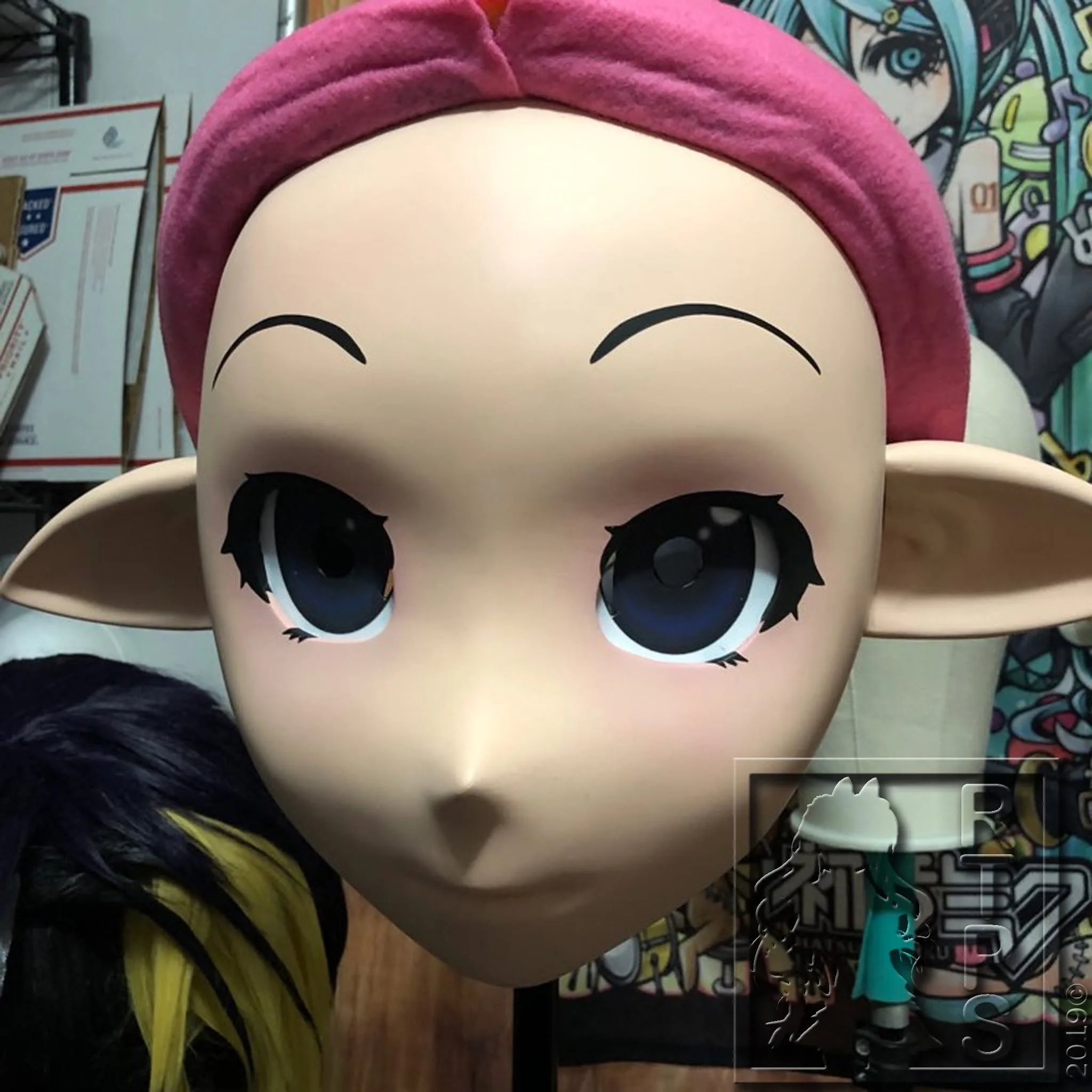Bare Ride the Pig Studio elf-ear animegao mask on a stand, 2019