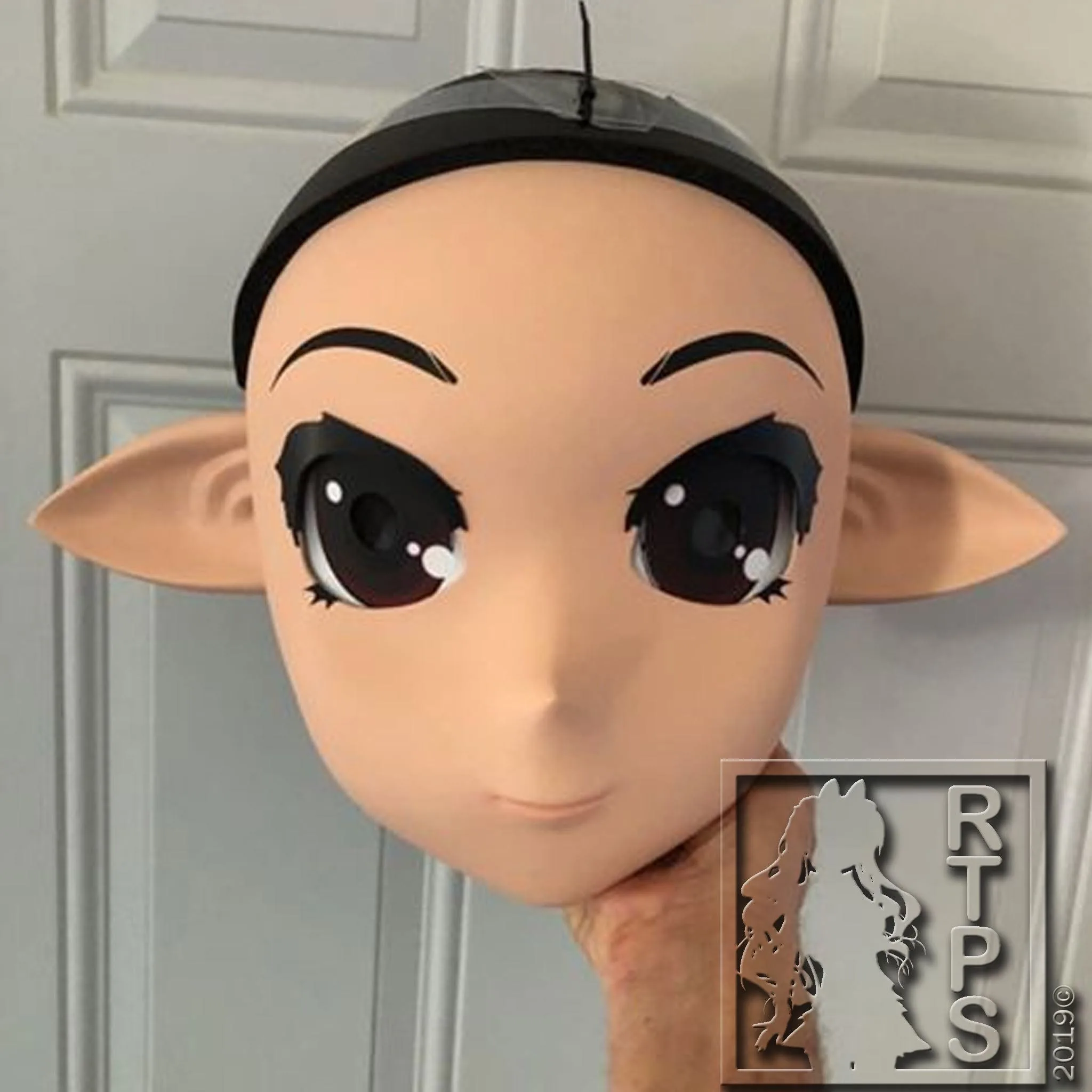 Ride the Pig Studio elf-ear animegao mask held up for inspection, 2019